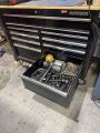 The fixtures are stored in the lower right drawer of the black Husky brand tool cabinet next to the welders